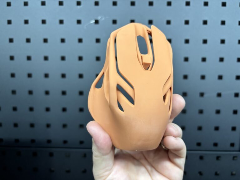 Orange 3D printed computer mouse shell with an open lattice design
