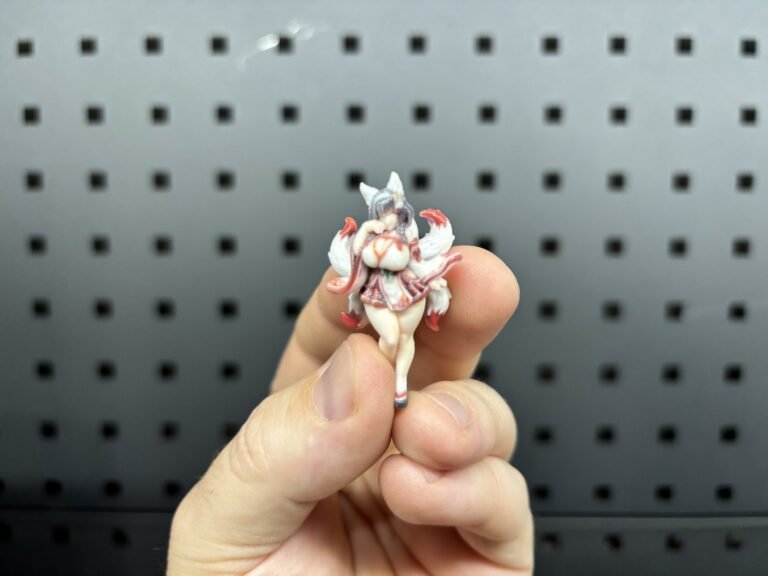 Very small full-colour 3D printed anime fox girl figure held between two fingers