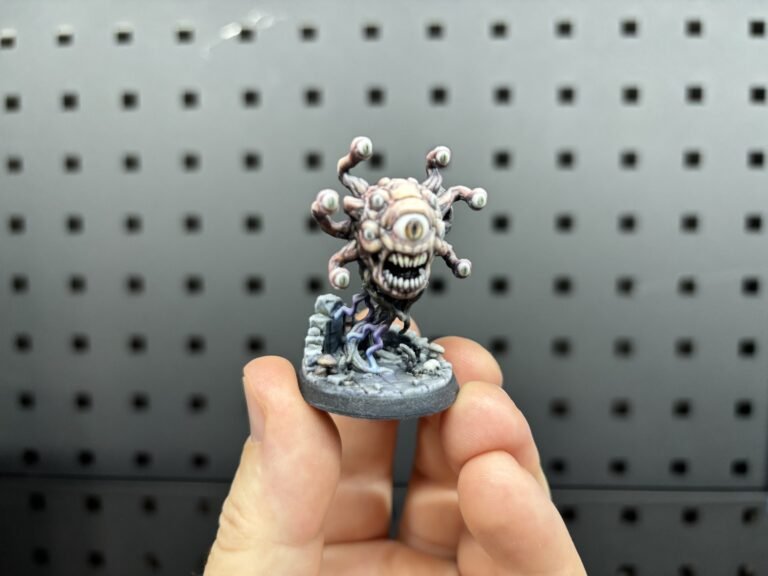 Full-colour 3D printed many-eyed monster miniature on a round base