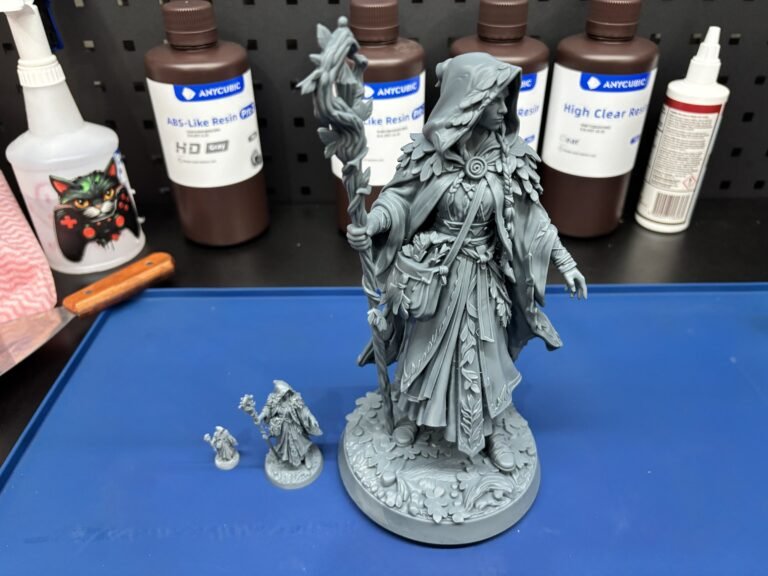 Large grey resin 3D print of a hooded druid beside two smaller miniature versions