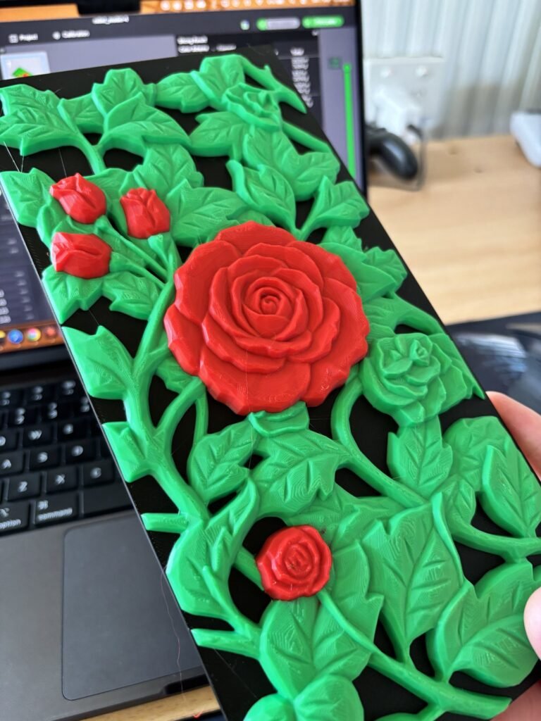 Multi-colour 3D printed relief wall art of red roses and green vines on a black background