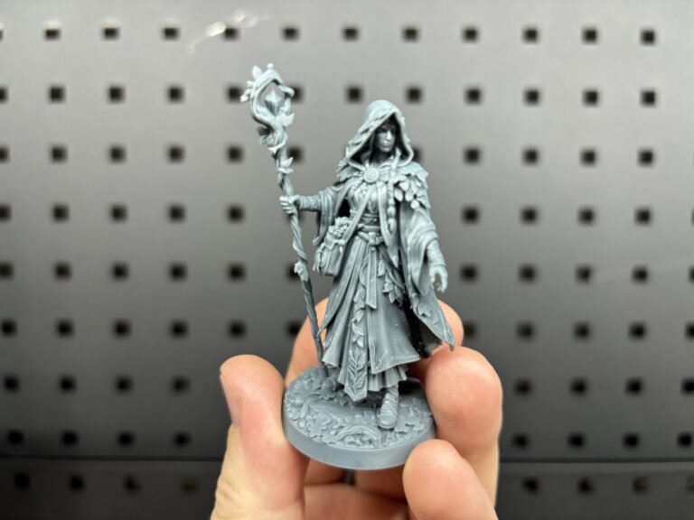 Grey resin 3D printed druid miniature with a staff, held in the hand
