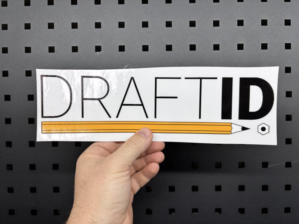 White sticker UV printed with the DraftID logo and a pencil graphic